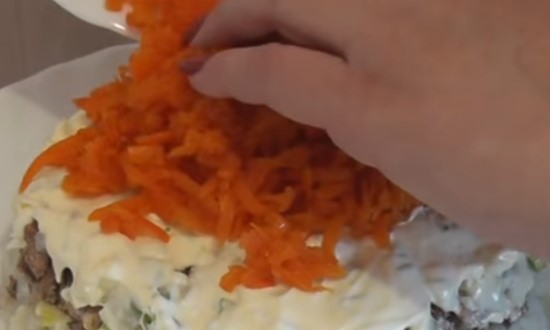 На слой из лука выкладываем натертую морковь